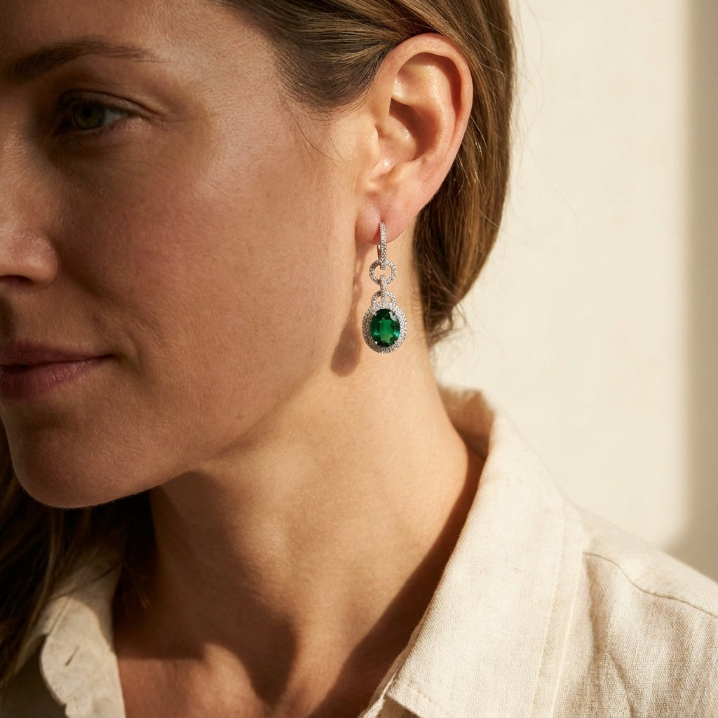 Platinum emerald and diamond drop earrings worn by a model in soft afternoon light, editorial lifestyle photo