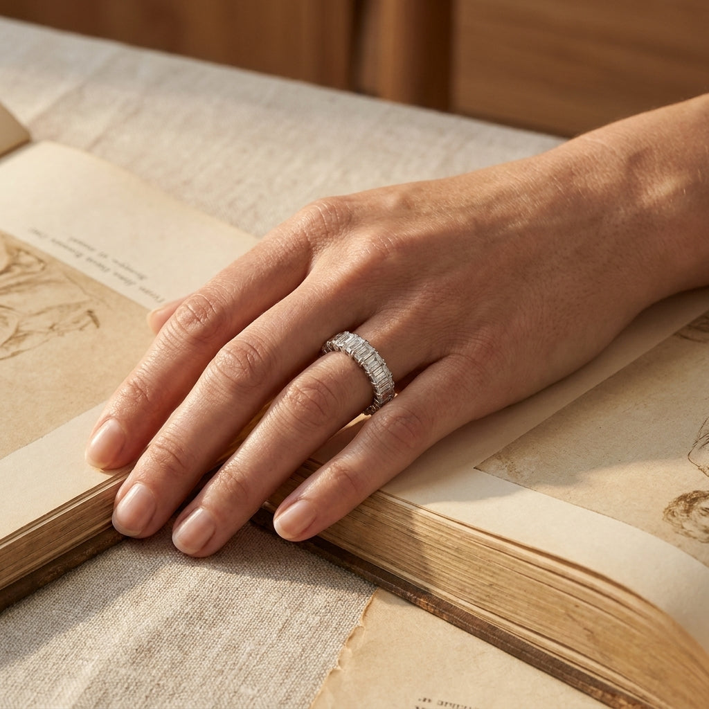 Platinum diamond eternity band worn on a hand resting on a book, editorial lifestyle photo