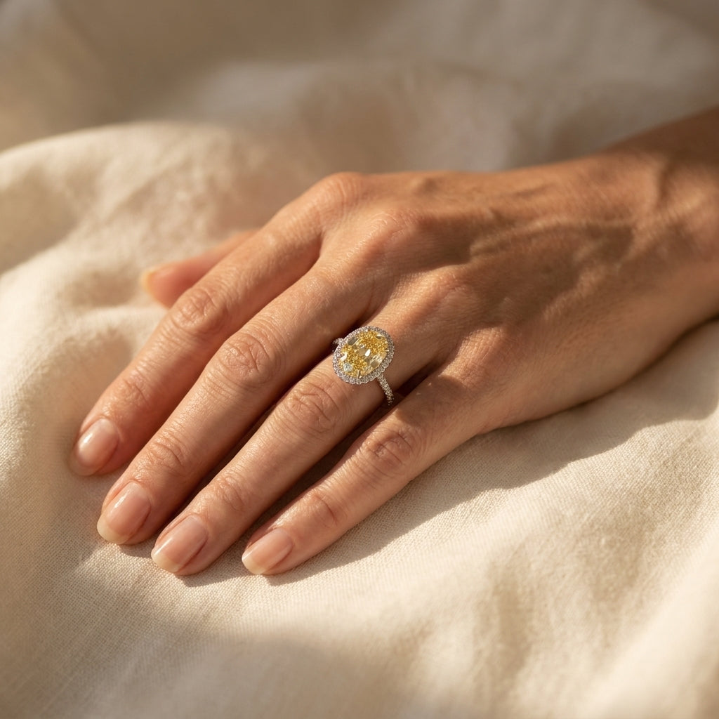 Oval natural fancy yellow diamond ring worn on a hand resting on linen, editorial lifestyle photo